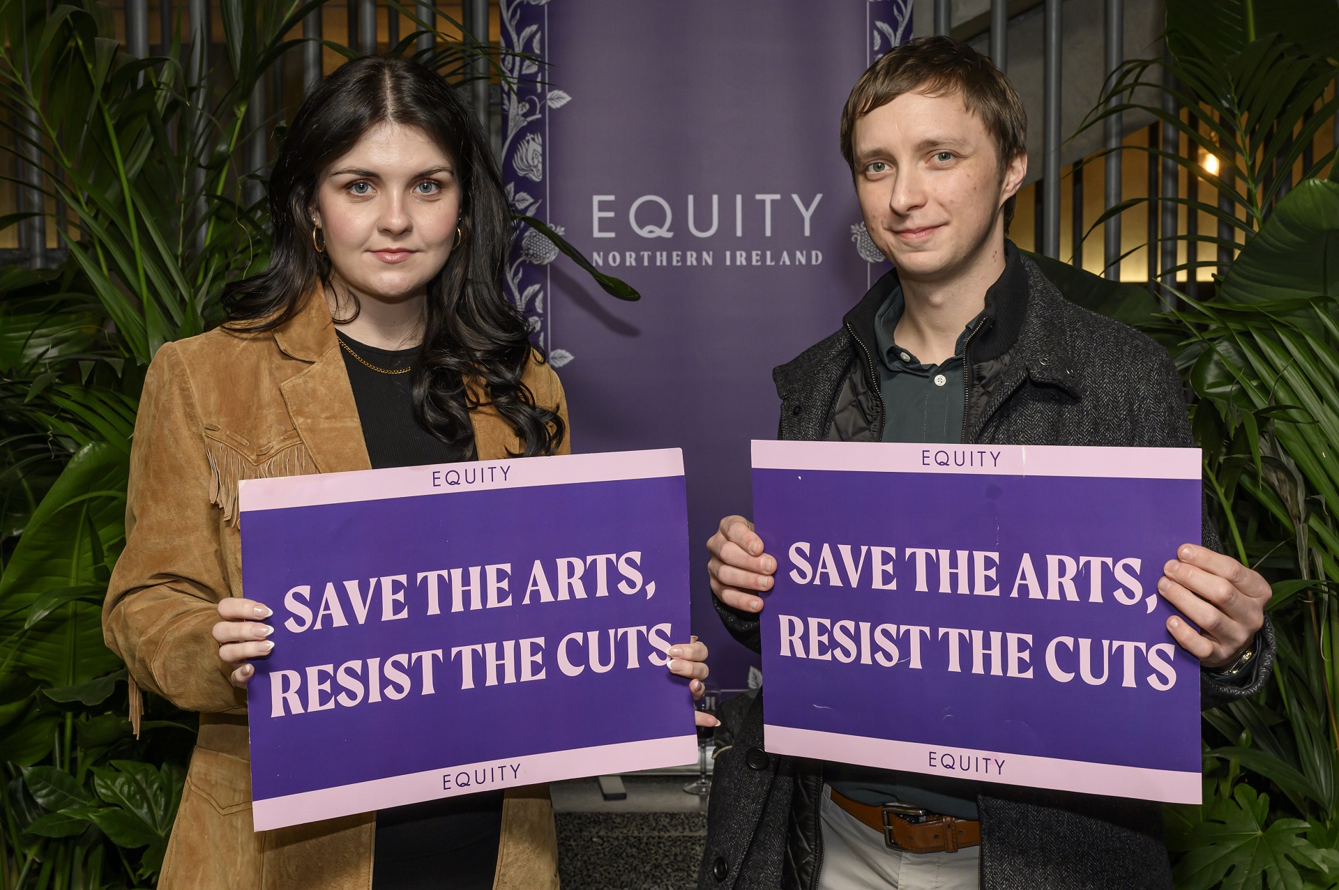 Two people hold signs saying "Save the arts, resist the cuts"