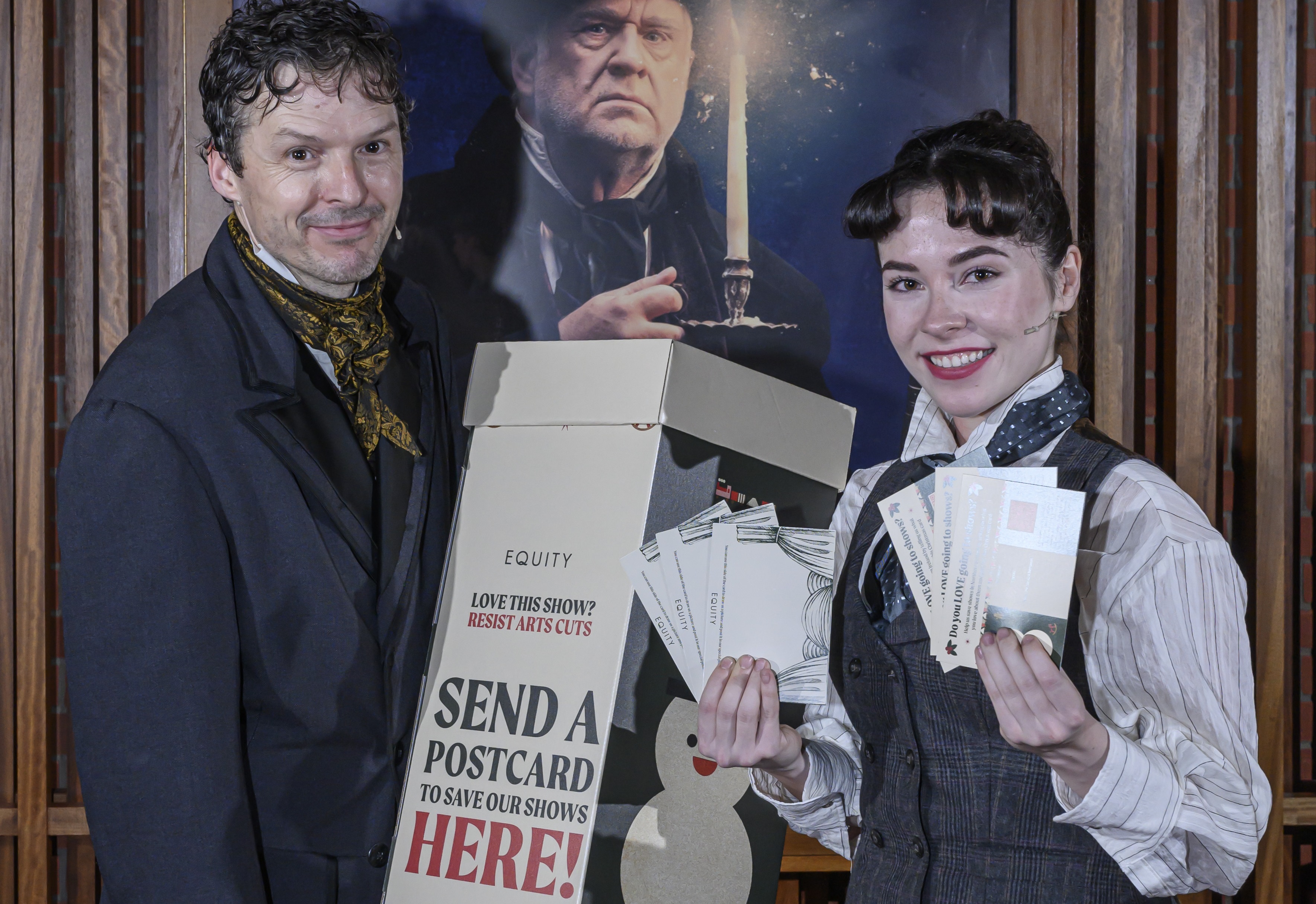 Two actors hold postcards and a postpox