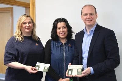 Two women and a man hold two Christmas postcards that read 'Do you LOVE going to shows'.