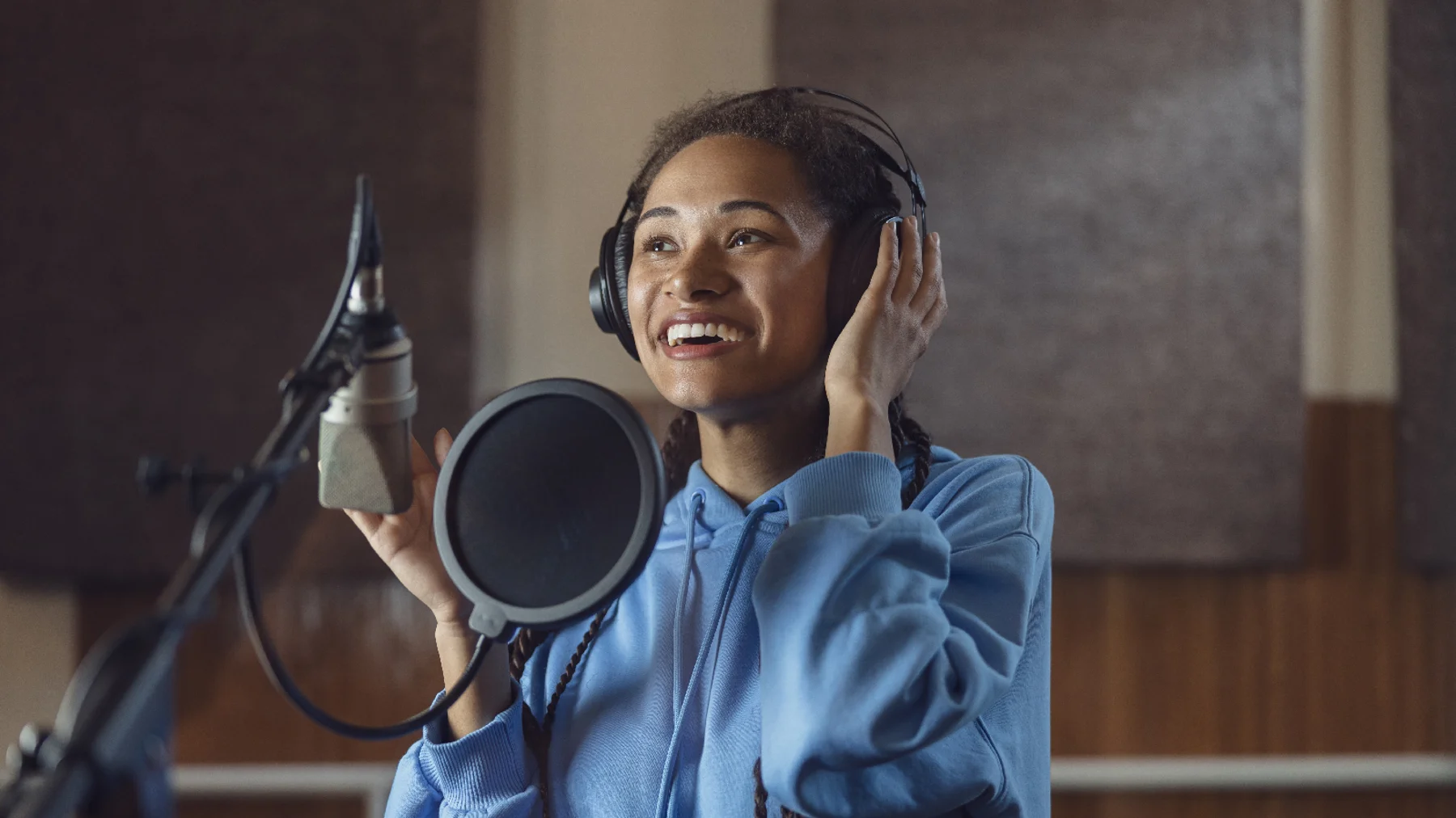 Woman audio artist at work in studio speaking into microphone